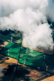 Aerial view of wind turbines standing tall near a vast field, symbolizing the synergy between renewable energy and agriculture