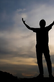 A strong human figure with his hands stretched towards the sky