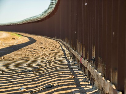 A weathered border barrier under the afternoon sun, reflecting the tightening of immigration policies across the region