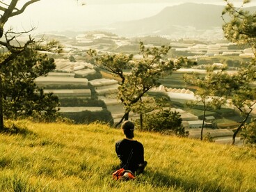 A person sitting alone on a hill overlooking the city, quietly reflecting in a peaceful moment