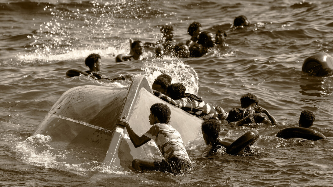Migrantes nadan cerca su embarcación de madera volcada durante un operativo de rescate de la ONG española Open Arms al sur de la isla italiana de Lampedusa, en el mar Mediterráneo, el 11 de agosto de 2022. Foto: Francisco Seco/Associated Press