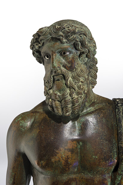Maestà di Giove (con fulmine e scettro). Firenze, Museo Archeologico Nazionale, inv. n. 2291 (già Roma, Collezione Ludovisi; poi a Firenze, acquistato nel 1669 dal Cardinal Leopoldo; quindi Galleria degli Uffizi, dal 1675). Alt. cm 29,3. Bronzo a fusione cava, realizzato in due parti (mantello e braccio a parte); occhi in argento; pupille e iridi (scomparse) in altri materiali pregiati; capezzoli e areole mammarie in rame. Pregevole opera romana di età augustea (fine I sec. a.C. – inizi I sec. d.C.), che copia un originale greco del 460-450 a.C., attribuito a Fidia giovane oppure a Mirone. Ph. Fernando Guerrini (Archivio Fotografico della Soprintendenza Archeologia della Toscana)