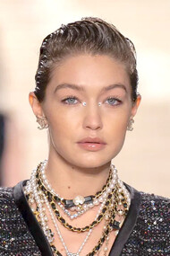 Modelo usa brincos Chanel, colares de pérolas e com detalhes pretos e dourados