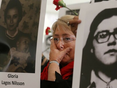 La presidente chilena Michelle Bachelet entre rostros de desaparecidos durante la dictadura