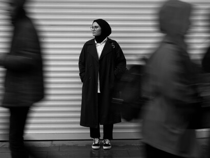 A woman quietly observing the bustling crowd around her, reflecting the importance of pausing to reconnect with oneself