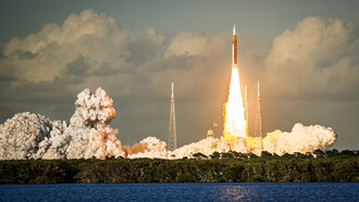 Apenas unos segundos después del despegue. Los motores principales del SLS y los propulsores de cohetes sólidos funcionan a plena potencia, lanzando columnas de llamas hacia abajo, mientras el sistema de supresión de ruido expulsa penachos blancos que se extienden hacia fuera por todo el complejo de lanzamiento.  Cuatro astronautas, la primera tripulación en abandonar la órbita terrestre desde el Apolo 17 en 1972, ya se elevan por el cielo de Florida por encima de una línea de árboles que solo puede ser el Kennedy Space Center, EE.UU.

