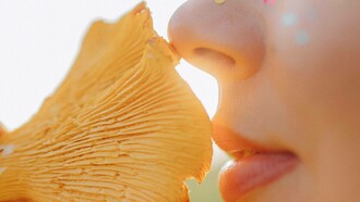 A woman smelling a delectable and fragrant brown mushroom