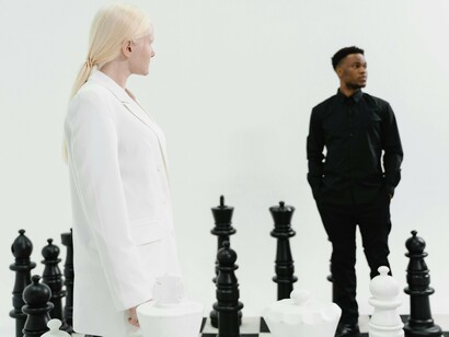 On a giant chessboard, figures dressed in stark black and white face off amidst towering pieces, symbolizing human ambition and the relentless drive to outthink and outperform, underscoring the importance of staying sharp and adaptable in the pursuit of success