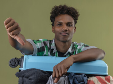 Young African American traveler holding a suitcase, passport, and visa documents at the airport