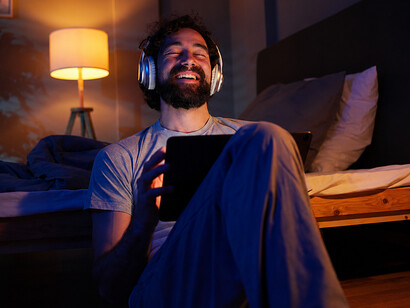 Young man relaxing while streaming a movie on a tablet and wearing headphones