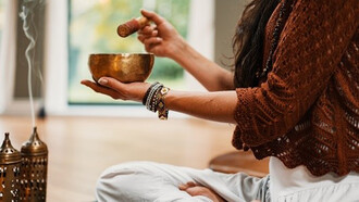 Woman in brown knit sweater holding brown ceramic cup making musical notes