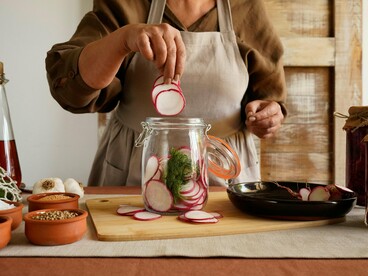 A woman arranging vegetables for fermentation, representing the process of feeding and supporting gut health