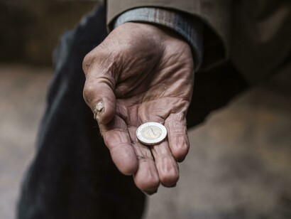 Mano di uomo anziano con moneta di due euro