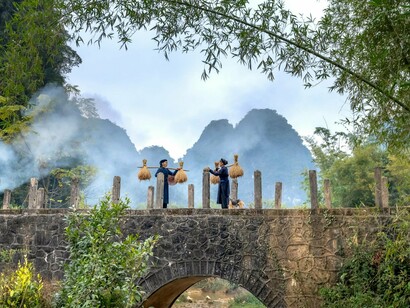 Farmers walking above the stream with their harvest balanced on bamboo poles, symbolising labour which became part of everyday survival