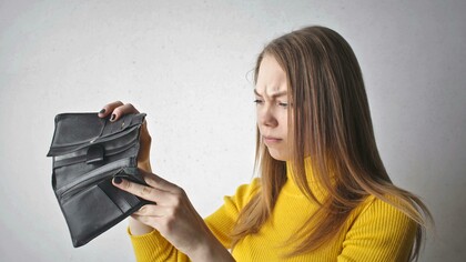 A woman holds an empty wallet, reflecting the financial challenges that lead to the lipstick effect