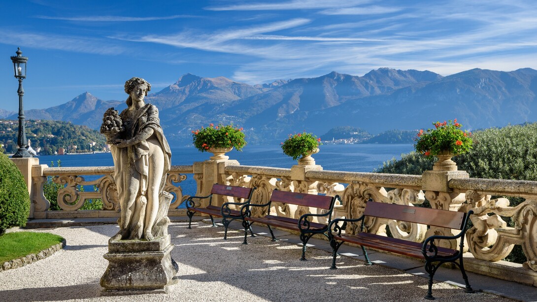 A statue sits on a bench overlooking Lake Como at Villa del Balbianello in Italy