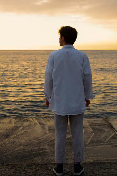 A man gazing at the horizon, lost in thought, as if finding freedom in the stillness of the sea