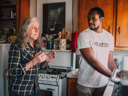 A kind-hearted volunteer providing home cleaning assistance to an elderly individual, promoting community care and support