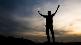 A strong human figure with his hands stretched towards the sky