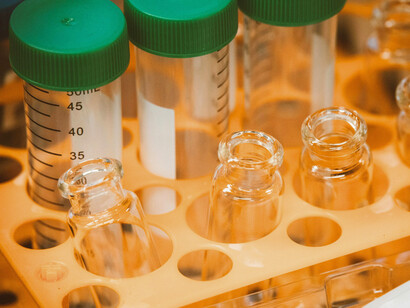 Plastic conical tubes, small and clear glass vials, arranged in a yellow test tube rack