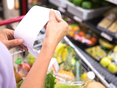 Woman shopping in a convenience store and checking her receipt, reflecting rising prices and inflation