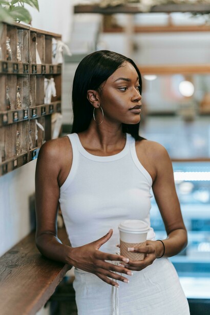 A woman enjoys a cup of coffee in a warm, cozy café setting