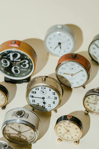 An arrangement of old-fashioned alarm clocks with their shadows, evoking the concept of time