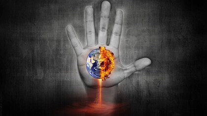 The hand of humanity holding the Earth as it is burning on fire