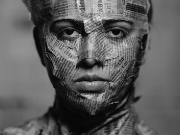 Recortes de jornais cobrem quase todo o corpo e o rosto da mulher. A sobreposição de discursos e informações parece disputar até a identidade individual. Com a pele revestida por fragmentos impressos, a mulher surge como extensão do excesso narrativo contemporâneo. Notícias, versões e ruídos tornam-se quase inseparáveis do cotidiano