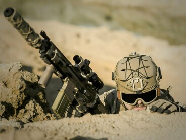 Soldier holding firearm while keeping a vigilant lookout, symbolising the uncertainty of the modern warfare