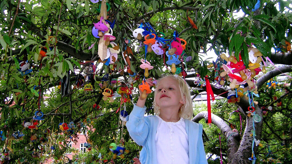 Una niña cuelga su chupete en el árbol