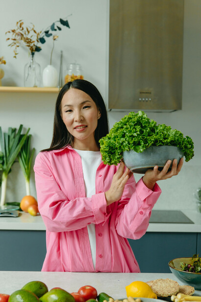 A woman holding a bowl of fresh lettuce, symbolizing vegan food, mindful nutrition, and a balanced plant-based lifestyle