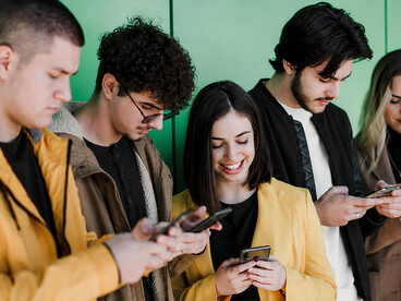 Young adults are absorbed in their smartphones, sharing the same space but not engaging in conversation