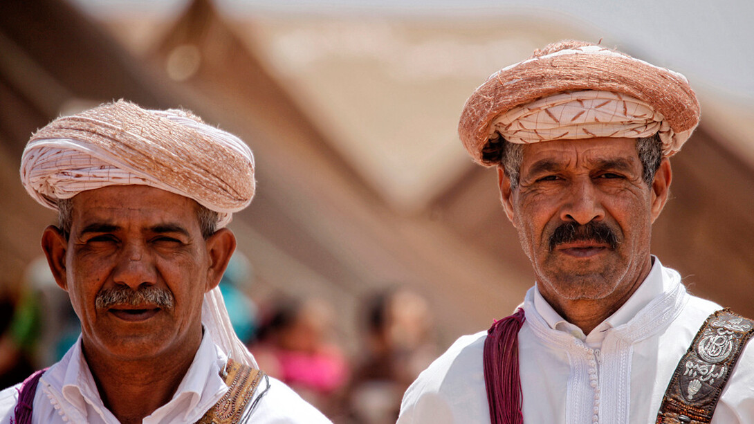 Two men immerse themselves in the vibrant culture of Tan-Tan, Morocco, during the Moussem de Tan-Tan on the 23rd of May, 2015, celebrating the city's rich heritage as a nexus of Saharan traditions and global influences