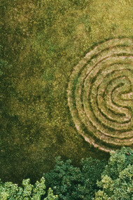 Un laberinto en espiral frente a la entrada de un bosque