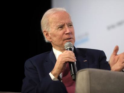 Joe Biden holding a microphone, in conversation, sitting down