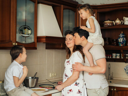 Cheerful family standing together in a warm, sunlit kitchen