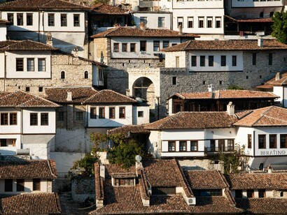 Closely packed white houses with terracotta roofs rising along the hillside, reflecting the streetscape and historic architecture of Berat, Albania