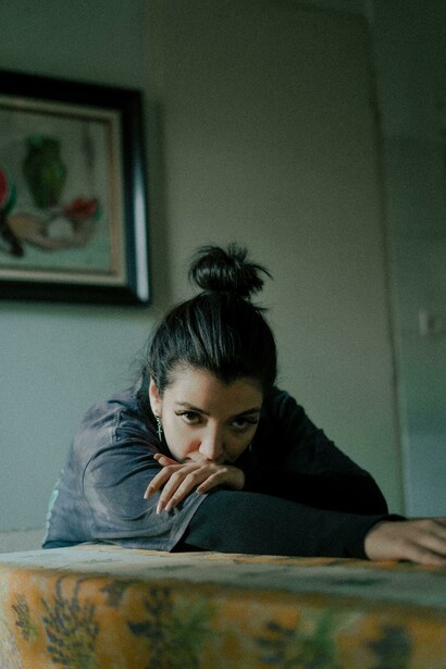 Young woman sitting alone in a dark apartment, reflecting themes of emotional isolation and abandoned motherhood