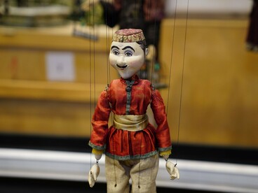 A smiling handcrafted puppet dressed in vibrant red attire, symbolizing the playful charm of traditional puppetry