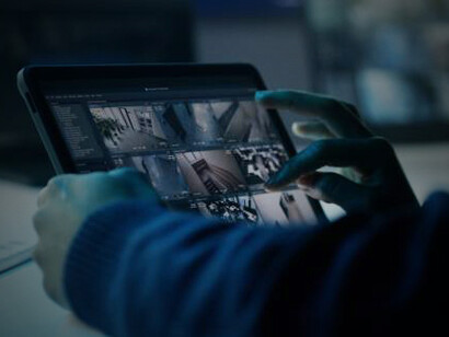 Using a tablet, the security operator fine-tunes the CCTV cameras to monitor and maintain secure surveillance