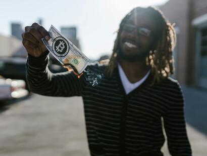 A man in a black striped shirt holds and burns a torn banknote, illustrating the impact of an economic crisis