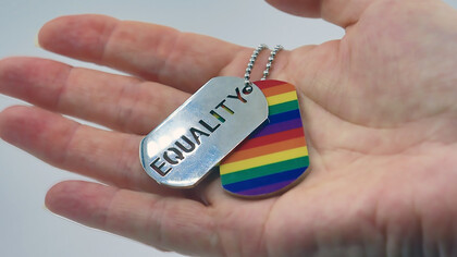 A person holding a rainbow tag in their hand, symbolizing the equality