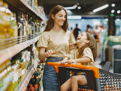 At the supermarket, a woman in a brown t-shirt and her family read labels while choosing products