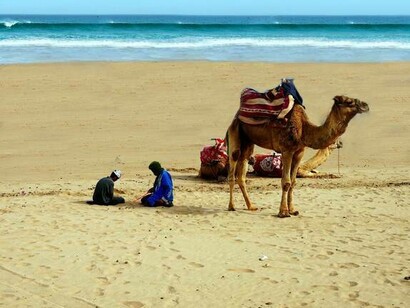 Camelo e pessoas em praia de Agadir, em Marrocos. A cidade tem uma história interessante, pois foi fundada por portugueses