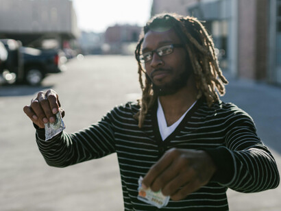 Man in a black striped long-sleeve shirt burning a torn banknote, symbolizing an economic crisis