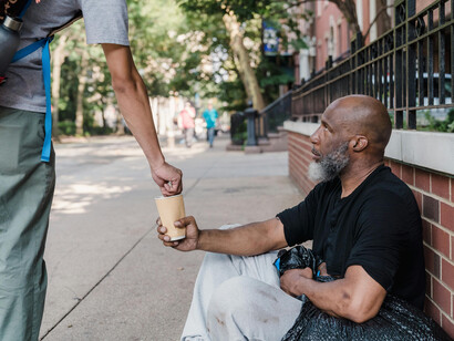 A middle aged black man receiving spare change from another person