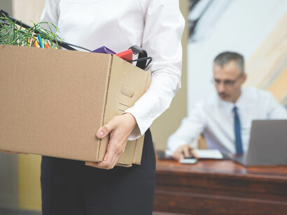 In the midst of an economic crisis and mass layoffs, visualize the tangible effects of inflation as a person carries a box, reflecting job losses and economic hardship