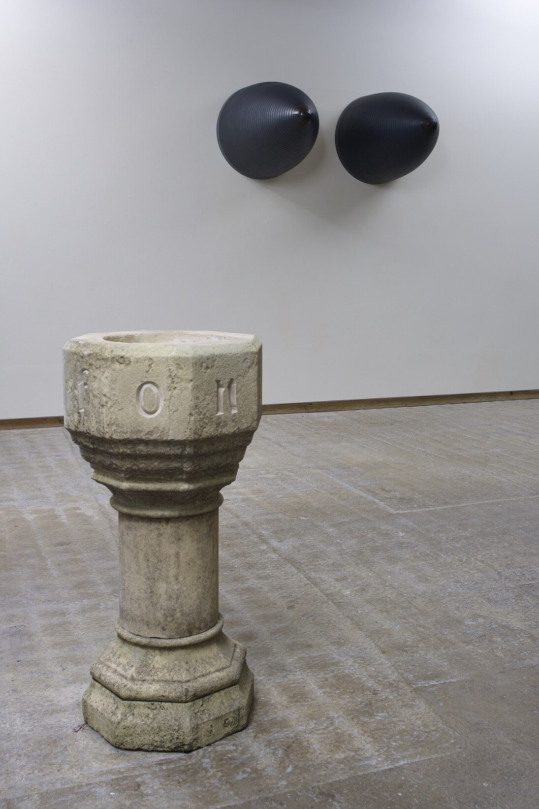 Fiona Banner, Installation shot with
Font 2015, Hand carved limestone baptismal font, 112 x 54 cm & Nose Art 2015, Graphite, Harrier Jump Jet nose cones, 107 x 79 cm (each), Courtesy the artist and Frith Street Gallery, London 
