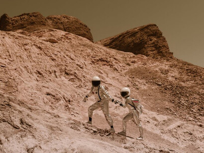 Astronauts walking hand-in-hand as they ascend a hill on Mars